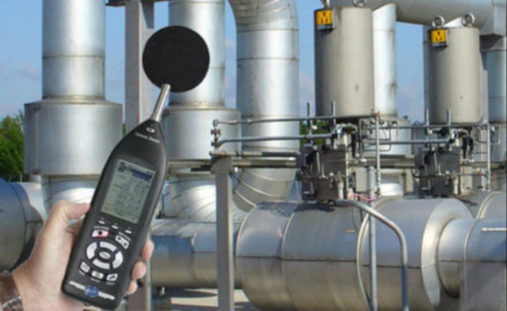 A professional conducting industrial noise testing in a factory in Qatar.