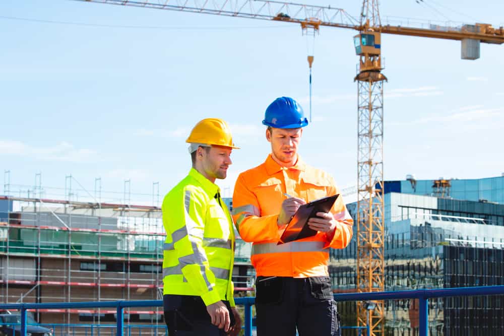 Safety officer conducting heat stress monitoring at an outdoor construction site in Qatar.