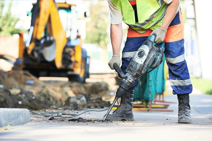 Worker using vibrating hand tool during HAVS risk assessment in Qatar.