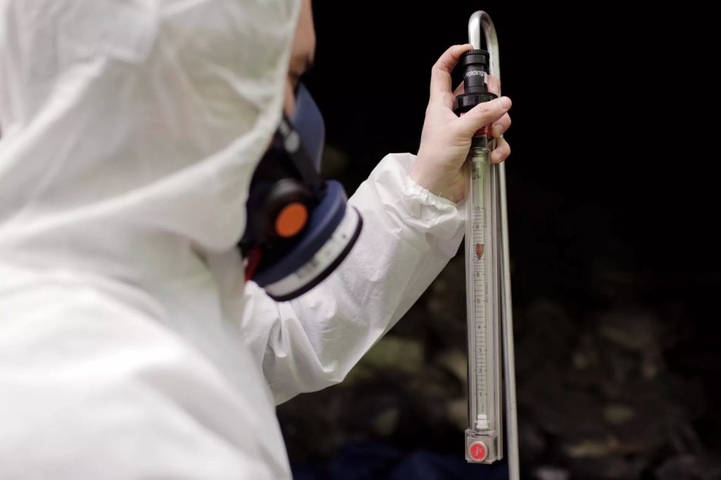 Occupational hygiene professional using air sampling equipment to assess asbestos fibres during W504 training.