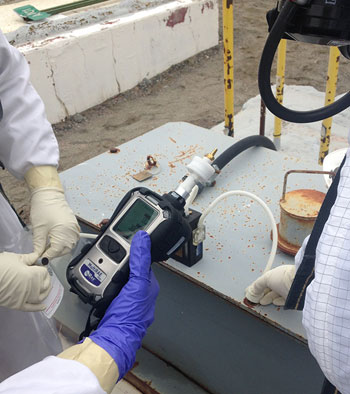 Industrial hygienist conducting chemical exposure monitoring using air sampling equipment in a workplace